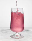 NUDE | Tom Dixon Splash Highball glass with pink sparkling liquid actively pouring in, set on a reflective marble surface.