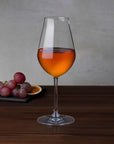 NUDE Salute sherry glass with amber wine beside red grapes and dried orange slice on a slate board
