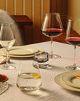 NUDE Salute wine glasses and tumbler on a set dining table with Joy votive candle, plates and olives