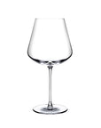 A clear NUDE Sera Red wine glass with a wide, gently flared bowl, a long slender stem, and a flat circular base, photographed on a plain white background.