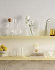 Cone shaped tall wine decanter in lead-free crystal, presented with an array of NUDE glassware products presented on a shelf with a soft white / yellow toned background